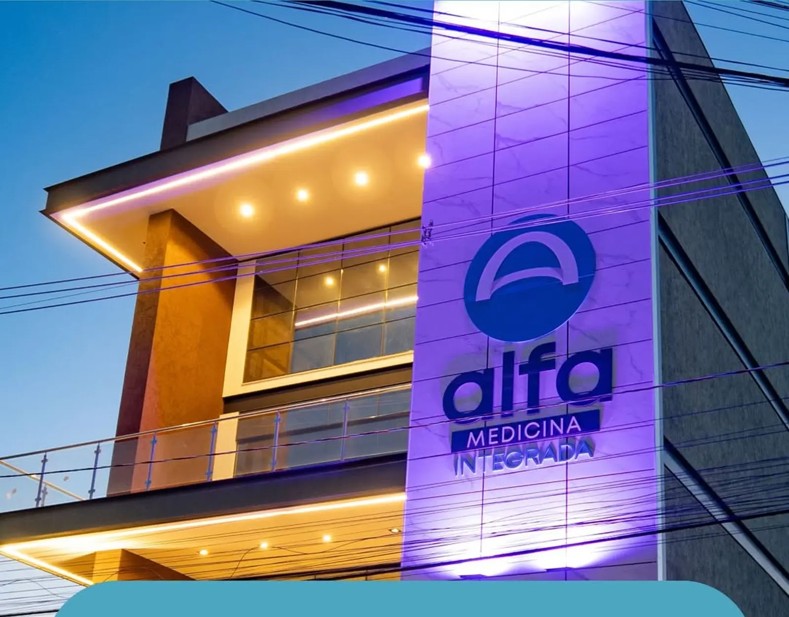 Fachada da Clínica Alfa em Irecê ao entardecer, com a torre iluminada da marca